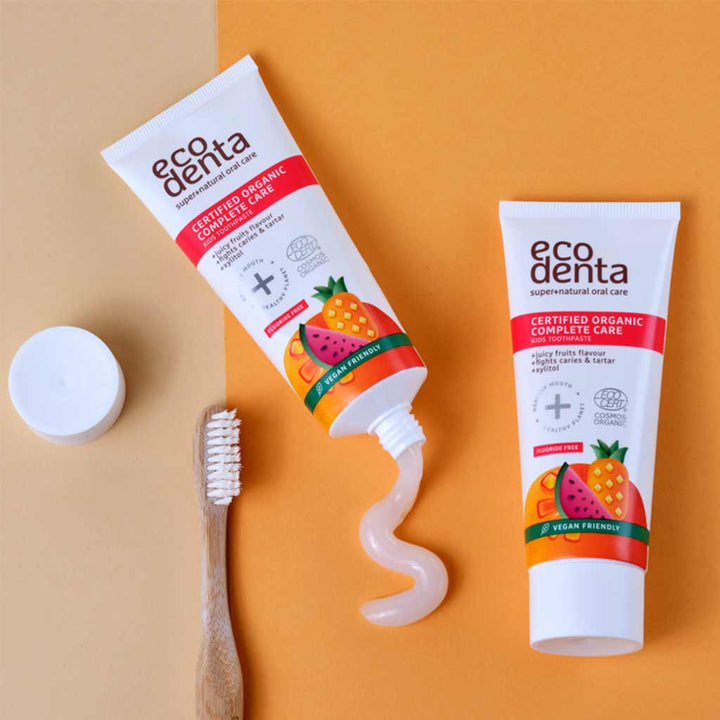 Oranssilla taustalla kaksi hammastahnatuubia, joista toisesta tulee valkoista hammastahnaa